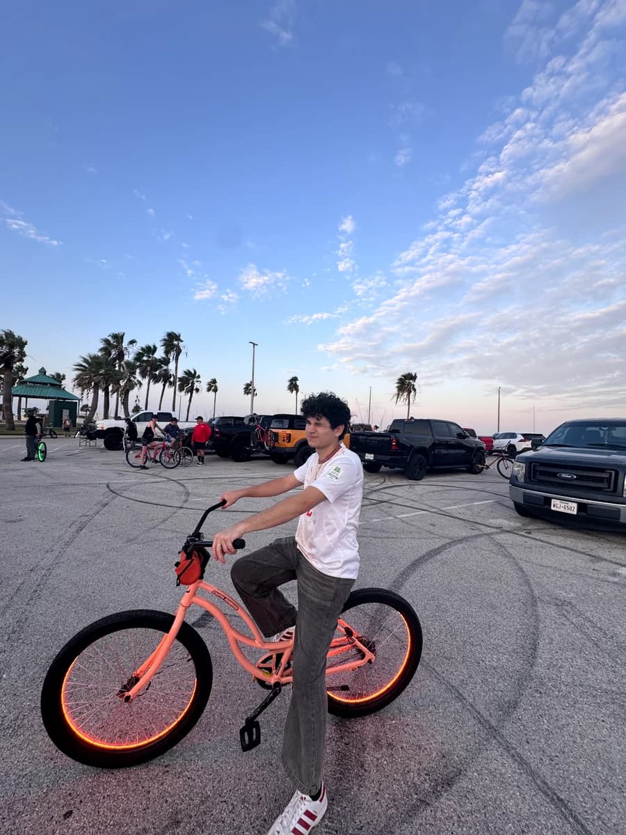 Alex on a coral-colored bike with glowing wheels beneath an evening sky