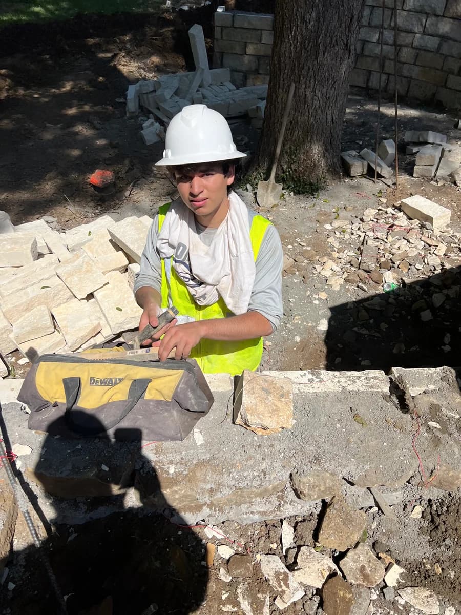 Alex working on a masonry site in a hard hat and safety vest